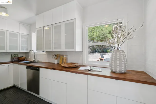 a kitchen with stainless steel appliances granite countertop a sink a window and white cabinets