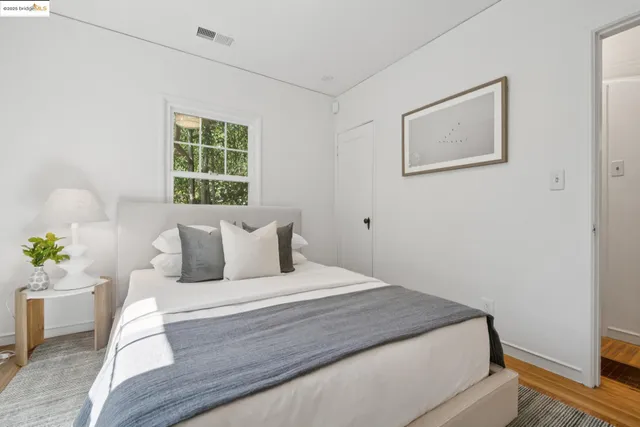 a bedroom with a bed painting on wall and a window