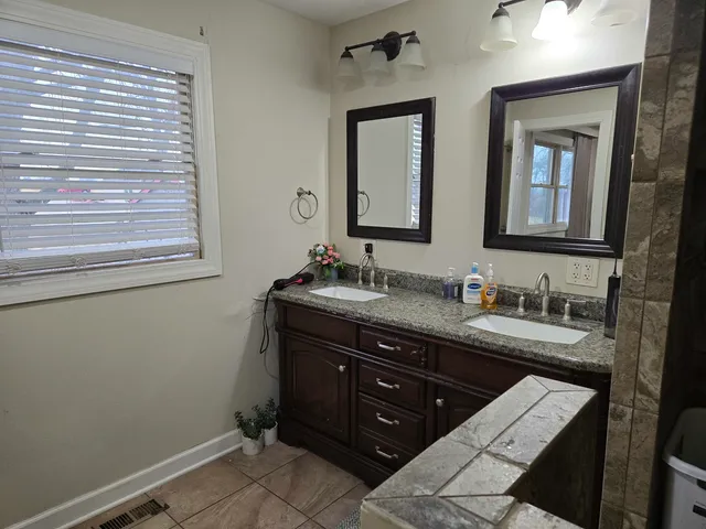 a bathroom with a granite countertop sink toilet a mirror and a window