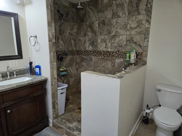 a bathroom with a granite countertop sink toilet and shower