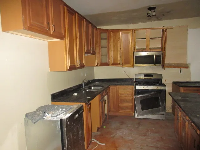 a kitchen with granite countertop a sink stove and microwave