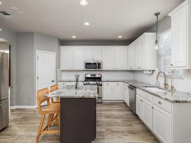 a large kitchen with stainless steel appliances granite countertop a sink stove and refrigerator