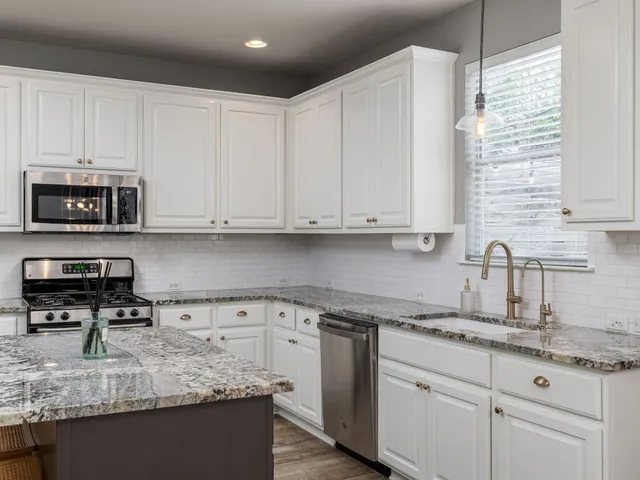 a kitchen with granite countertop white cabinets and a sink