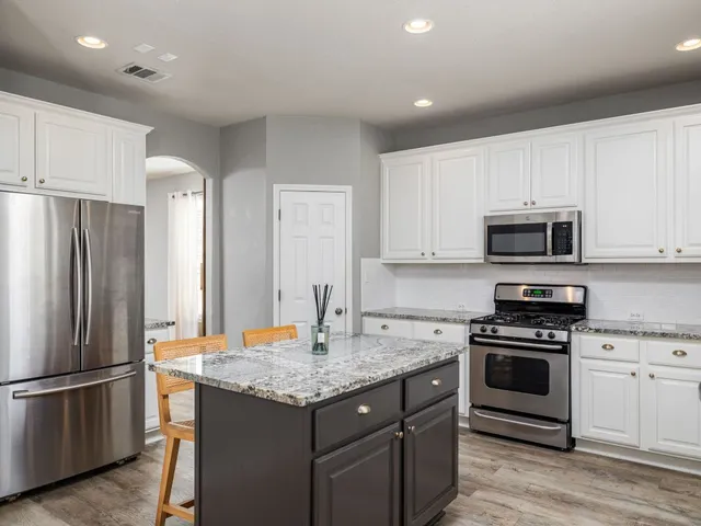 a kitchen with stainless steel appliances granite countertop a refrigerator stove and microwave
