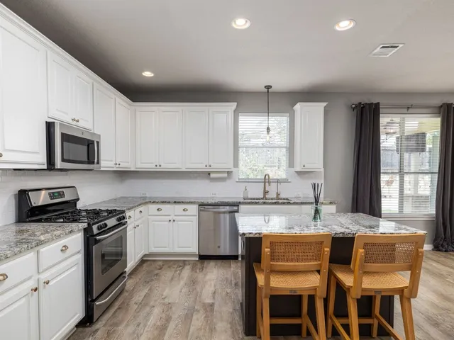 a kitchen with granite countertop white cabinets and appliances
