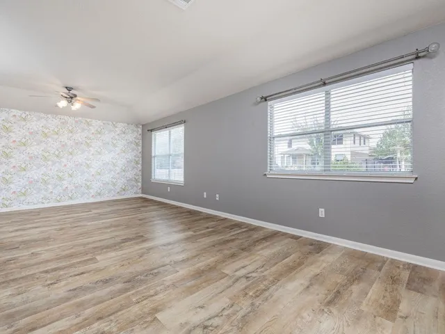 a view of empty room with wooden floor and fan