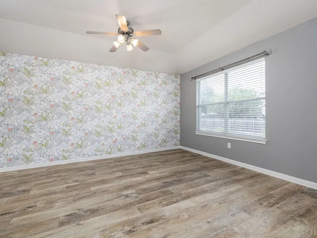 a view of a big room with wooden floor and a chandelier fan
