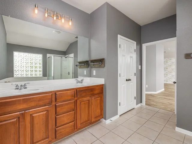 a spacious bathroom with a shower a sink and a mirror