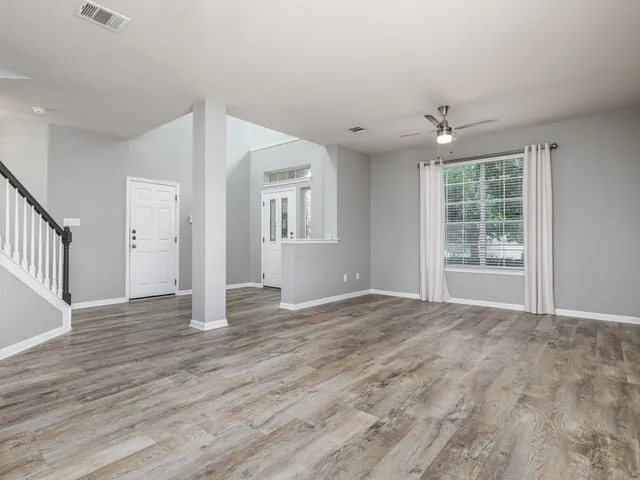 a view of an empty room with wooden floor and a window