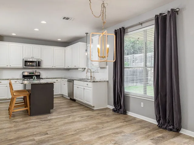 a kitchen with kitchen island granite countertop a refrigerator cabinets and wooden floor