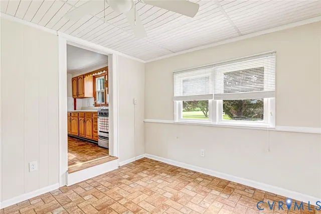 a view of an empty room with kitchen and a window