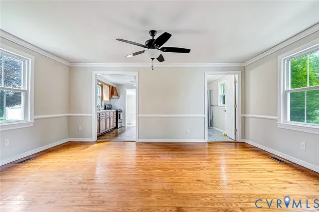 a view of empty room with wooden floor and fan