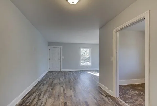 a view of hallway with window and wooden floor