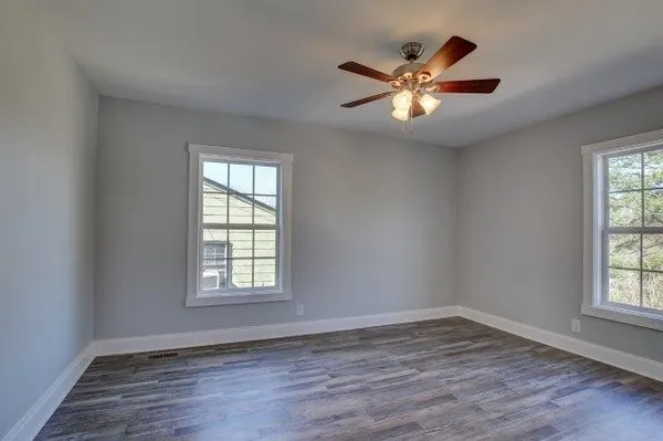a view of empty room with wooden floor and fan