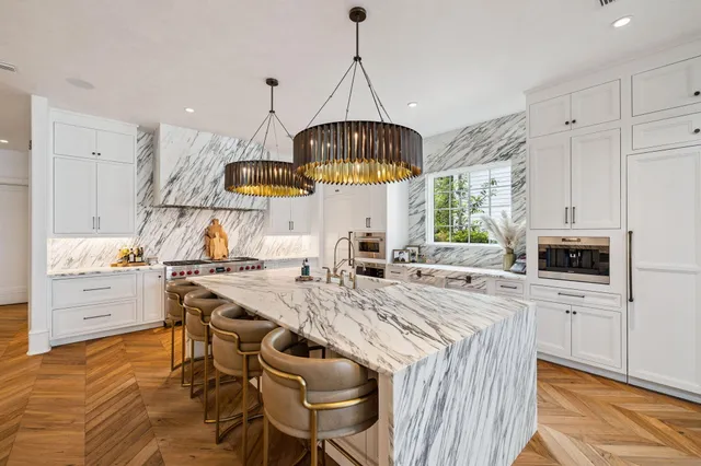 a kitchen with stainless steel appliances a stove a sink dishwasher a oven with a dining table and chairs