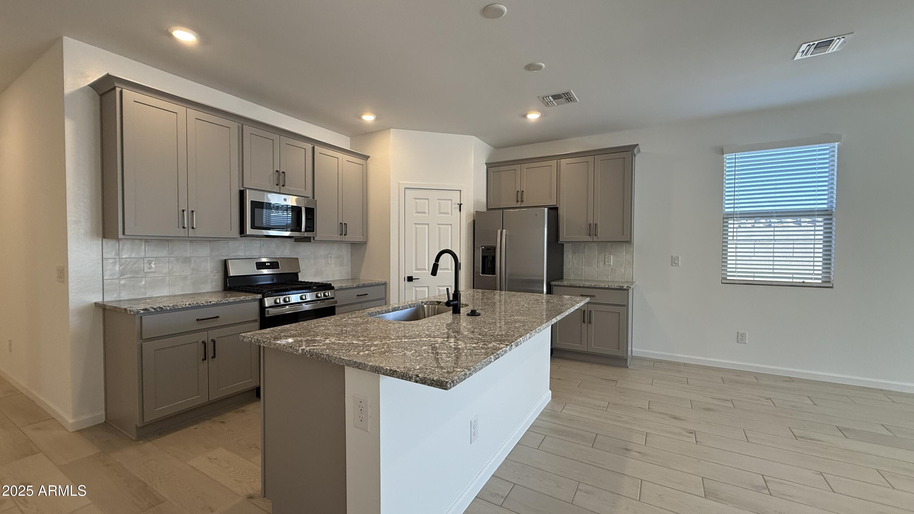 46819 West Old Timer Road Maricopa, AZ 85139 - Photo 11 of 44 a kitchen with kitchen island granite countertop a sink stove and cabinets