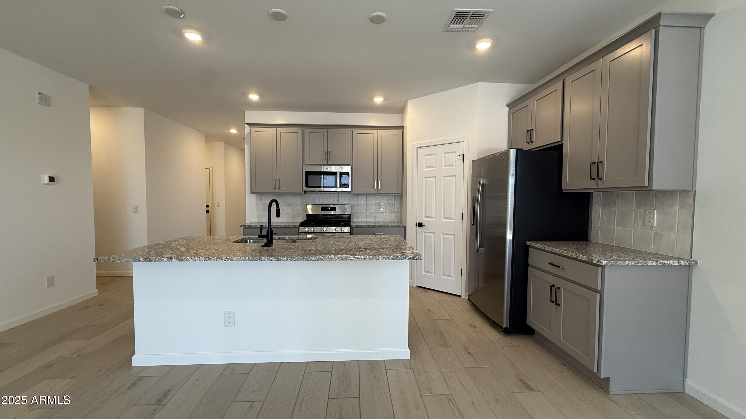 46819 West Old Timer Road Maricopa, AZ 85139 - Photo 12 of 44 a kitchen with stainless steel appliances granite countertop a refrigerator a sink and a stove