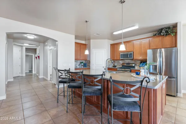 a kitchen with stainless steel appliances a refrigerator a stove a sink a dining table and chairs