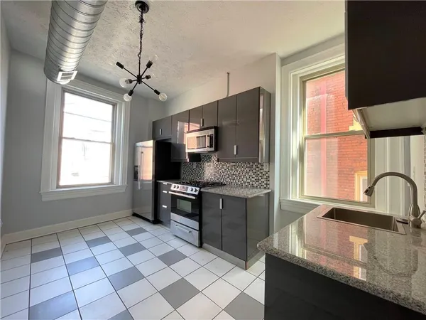 a kitchen with granite countertop a sink appliances cabinets and a counter top space