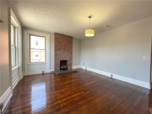 an empty room with wooden floor fireplace and window