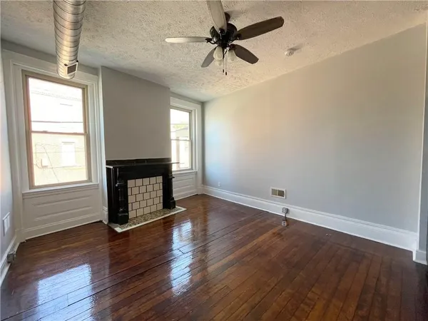 an empty room with wooden floor a ceiling fan and windows