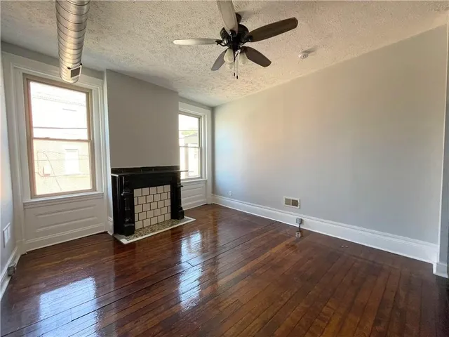 an empty room with wooden floor a ceiling fan and windows