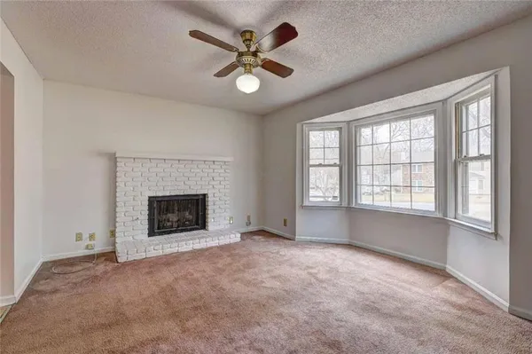 a view of an empty room with a fireplace and a window
