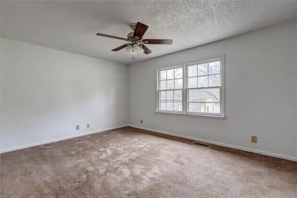 an empty room with a window and a fan