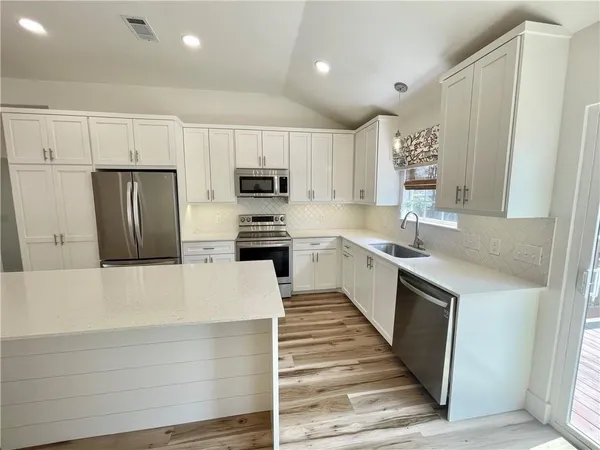 a large kitchen with a large window and stainless steel appliances