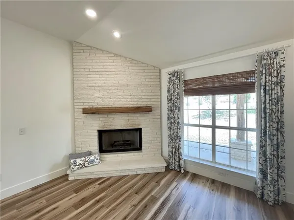an empty room with wooden floor fireplace and windows
