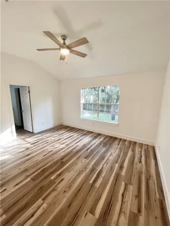 an empty room with wooden floor fan and windows
