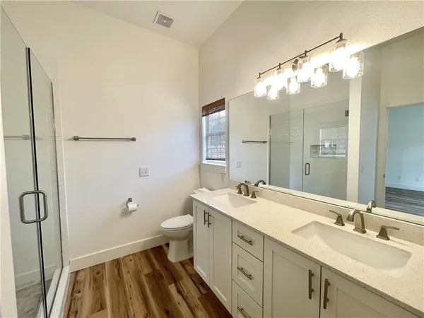 an empty room with wooden floor a ceiling fan and windows
