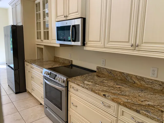 a kitchen with granite countertop white cabinets and stainless steel appliances