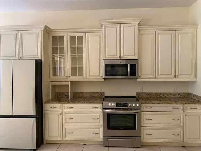 a kitchen with granite countertop white cabinets and stainless steel appliances