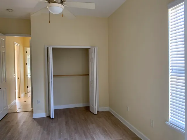 an empty room with wooden floor fan and windows