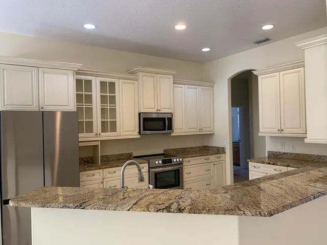 a kitchen with stainless steel appliances granite countertop a refrigerator a stove and a sink