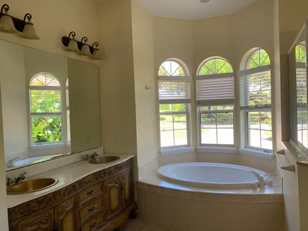 a bathroom with a granite countertop tub a sink and a window