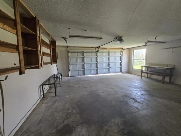 an empty room with windows and chandelier fan
