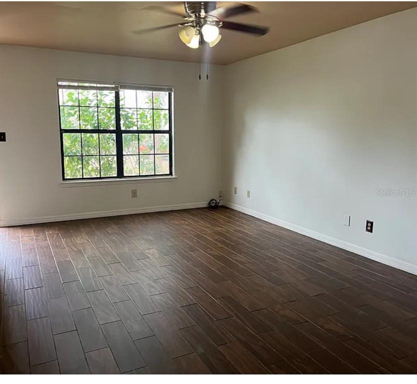 2302 South Maki Road, Unit 98 Plant City, FL 33563 - Photo 3 of 7 an empty room with wooden floor chandelier fan and windows