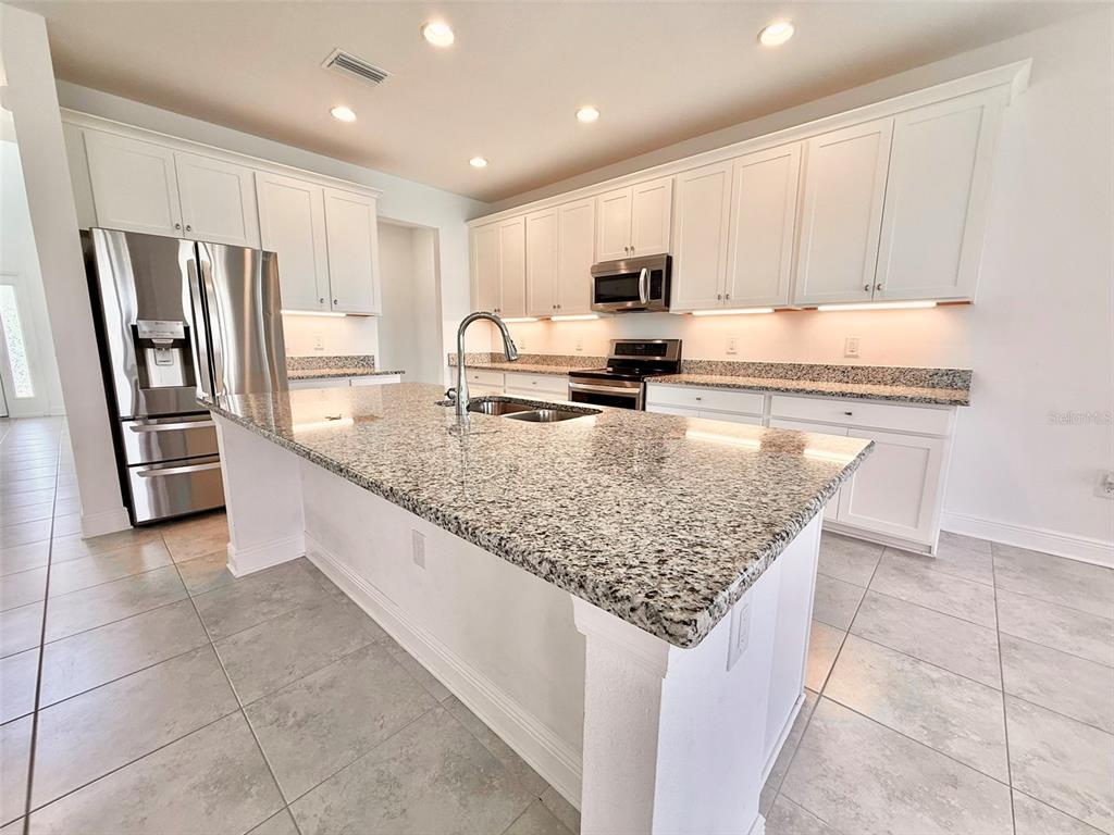 12189 Nouveau Avenue Spring Hill, FL 34610 - Photo 14 of 50 a kitchen with stainless steel appliances granite countertop a sink stove and refrigerator