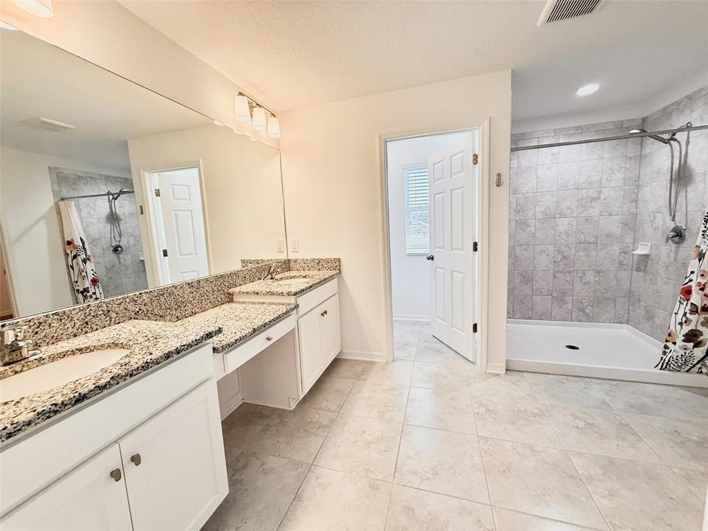 12189 Nouveau Avenue Spring Hill, FL 34610 - Photo 29 of 50 a bathroom with a granite countertop sink a toilet and shower