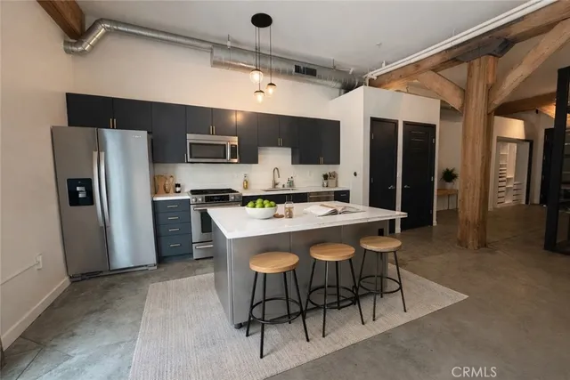 a kitchen with stainless steel appliances kitchen island a table chairs and a refrigerator