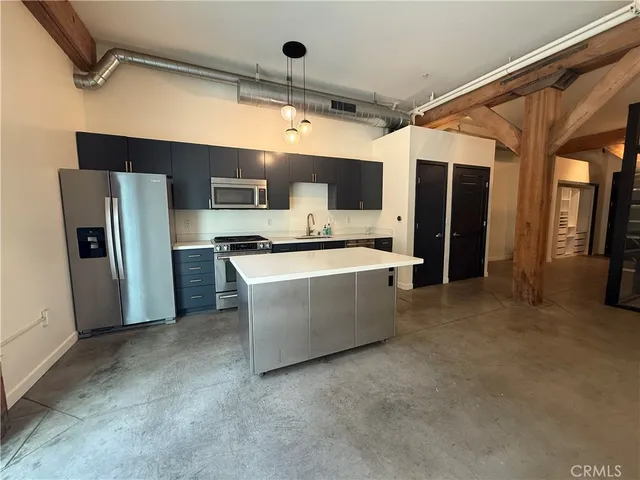 a room with stainless steel appliances kitchen island a refrigerator and a sink