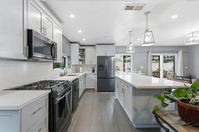 a kitchen with kitchen island granite countertop a sink a counter space stainless steel appliances and cabinets