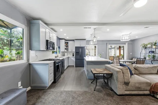 a large open kitchen with stainless steel appliances granite countertop a stove top oven a sink dishwasher a dining table and chairs with wooden floor