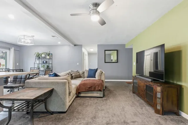 a living room with furniture a flat screen tv and kitchen view