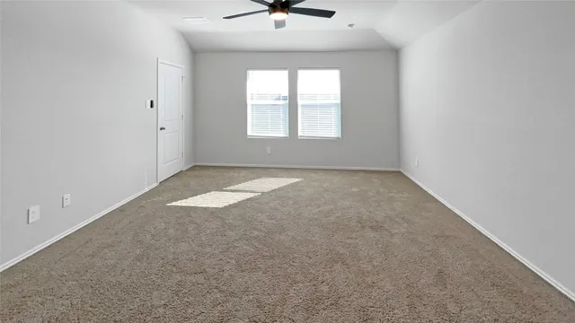 an empty room that has a window and a ceiling fan