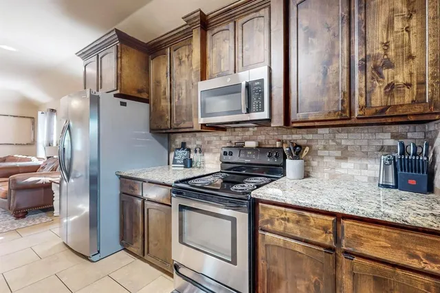 a kitchen with stainless steel appliances granite countertop a stove a sink and a microwave