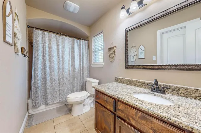 a bathroom with a granite countertop sink a toilet and a mirror