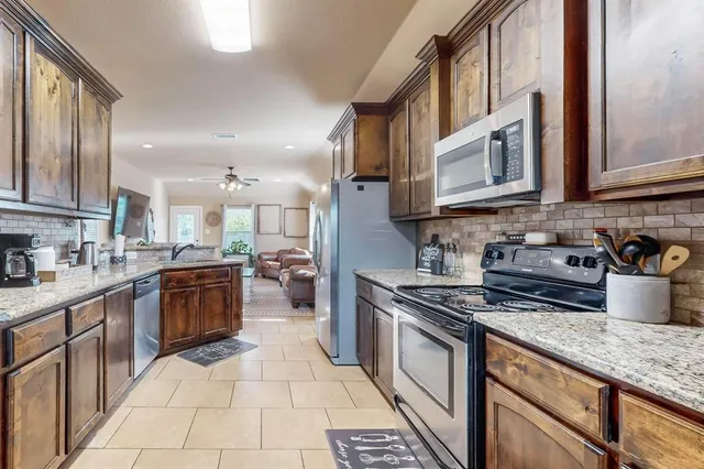 a kitchen with stainless steel appliances granite countertop a stove a sink and a microwave
